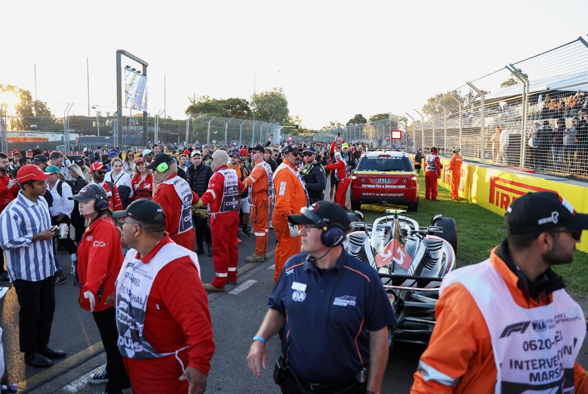 Los comisarios de pista y personal de seguridad rodean el Haas de Hulkenberg que debió aparcar en la curva dos para conservar combustible para la técnica. (Lionel Ng)